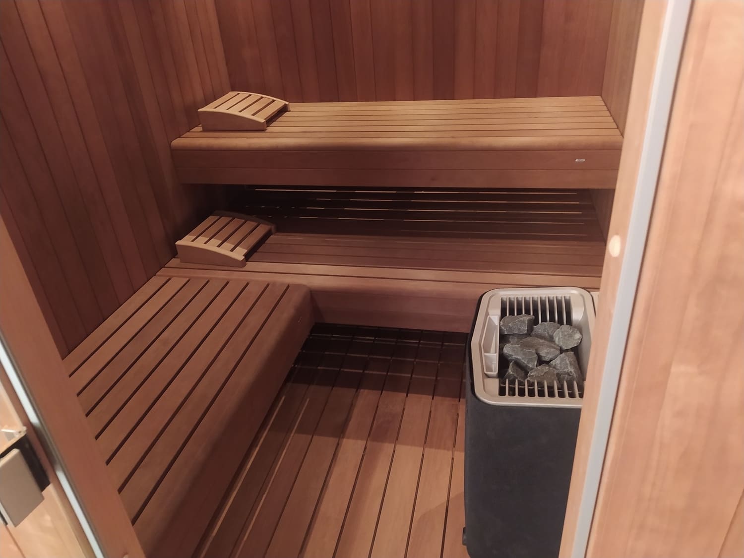 interno sauna con pavimento grogliato e panche a elle